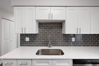 a black and white kitchen with white cabinets and a sink